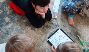 A group of four tiny humans write a list of priorities for the day, including "spying."
